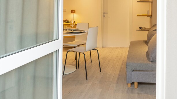 En modern inredning med ett matområde, en soffa och ett träpanelat tak.