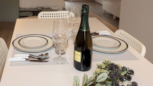 Ett dukat matbord med tallrikar, bestick, vinglas, en vinflaska och en blomsteruppsättning.