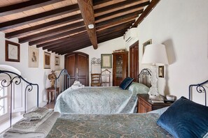 Une chambre à coucher avec un lit, des poutres en bois au plafond, une fenêtre et un climatiseur fixé au mur.