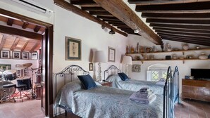 Une chambre avec deux lits, un pupitre à musique et une étagère où sont exposées des pièces de poterie.