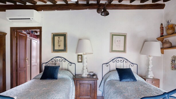A bedroom with two beds, a wooden wardrobe, a bedside table with a lamp, and a shelf with decorative items. - Auri Room – Marinsky with Shared Garden, Wi-Fi and Air Conditioning (Pietrasanta)