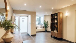 Eine Hotelhalle mit einer Rezeption, einer Holztruhe mit Regalen und einer großen Topfpflanze.