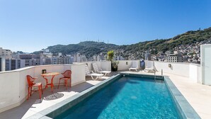 En pool på taket med fri utsikt över staden och kullarna i bakgrunden.