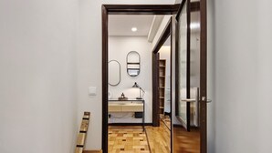 A hallway leading to a bathroom with a wooden floor, a desk, and a mirror. - Apartment 'Station 54' with Balcony and Wi-Fi (Porto)