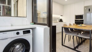 A compact kitchen with a microwave, oven, and a dining area with chairs. - Apartment 'Station 54' with Balcony and Wi-Fi (Porto)
