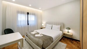 A hotel room with a bed, a desk, a chair, a nightstand with a lamp, and a window with curtains. - Apartment 'Station 54' with Balcony and Wi-Fi (Porto)