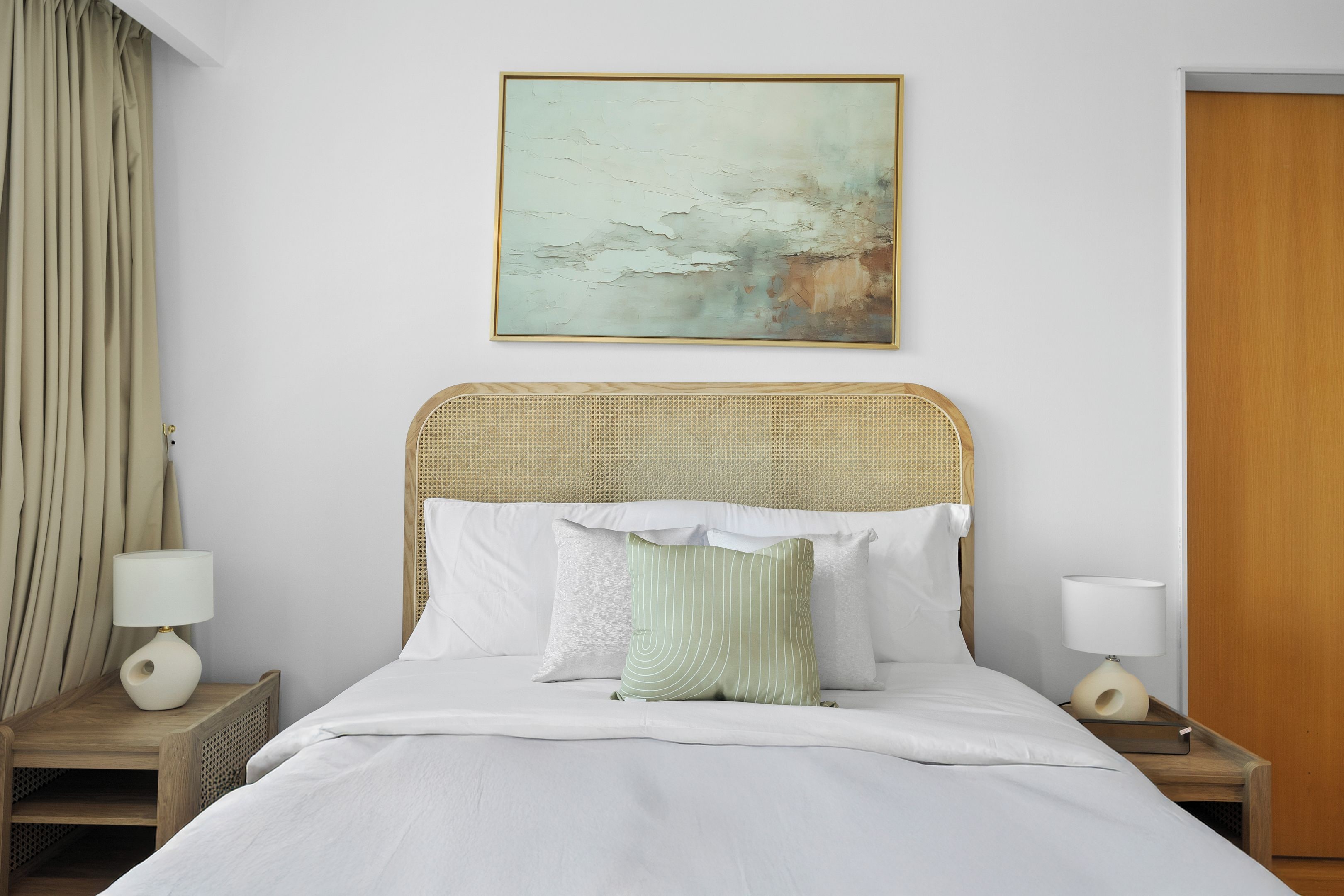 A hotel room with a bed, two bedside tables, a wall-mounted painting, and a wooden door.