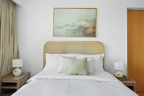A hotel room with a bed, two bedside tables, a wall-mounted painting, and a wooden door. - 1011 Bloomfields1BR Al Nada Raha Beach  (Madinat Zayed)