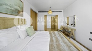 Hotellihuoneessa on sänky, työpöytä ja peili. Seinällä on taulu ja katossa kattovalaisin.