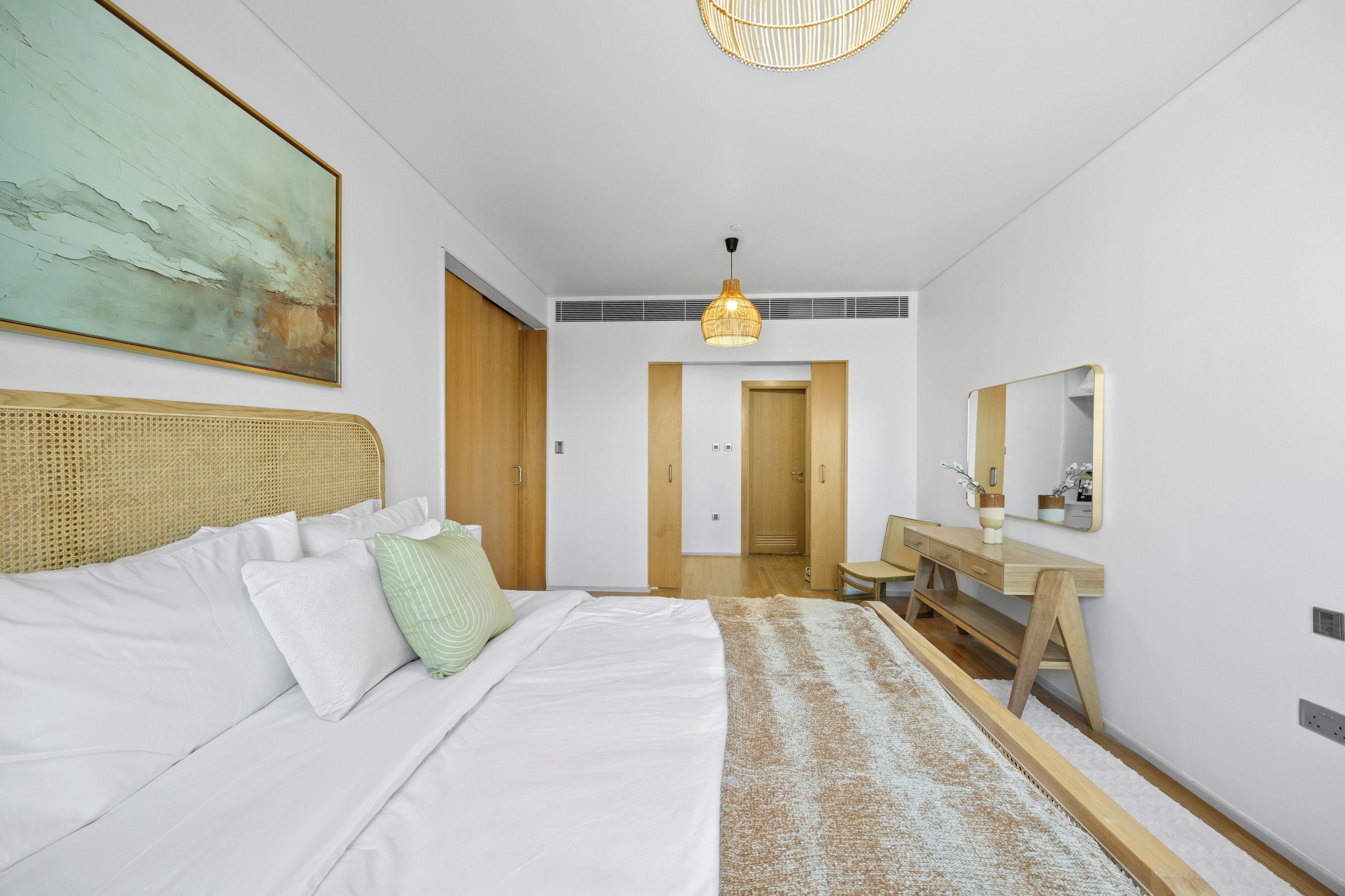 A modern bedroom with a bed, bedside table, and a large mirror.