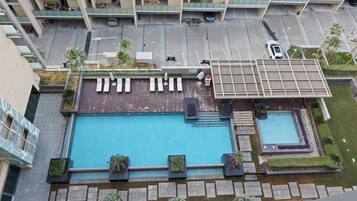 A rooftop swimming pool with lounge chairs and a small adjacent pool.