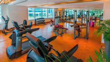 A gym with cardio machines, weightlifting equipment, and dumbbells.