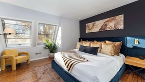 A modern bedroom with a large bed, a sofa, a potted plant, and a wall-mounted artwork. - Mars Hill Retreat: Sauna, Wet Bar, Hot Tub, Views (Mars Hill)