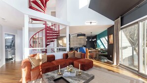 A modern living room with a red spiral staircase, a sectional sofa, and a marble coffee table. - Mars Hill Retreat: Sauna, Wet Bar, Hot Tub, Views (Mars Hill)