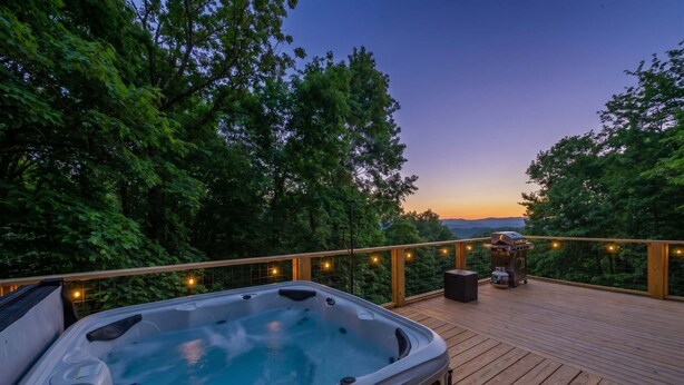 A hot tub on a wooden deck with a view of trees and a sunset. - Mars Hill Retreat: Sauna, Wet Bar, Hot Tub, Views (Mars Hill)