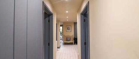 A hallway with two doors on either side, leading to a room with a bed and a chair.