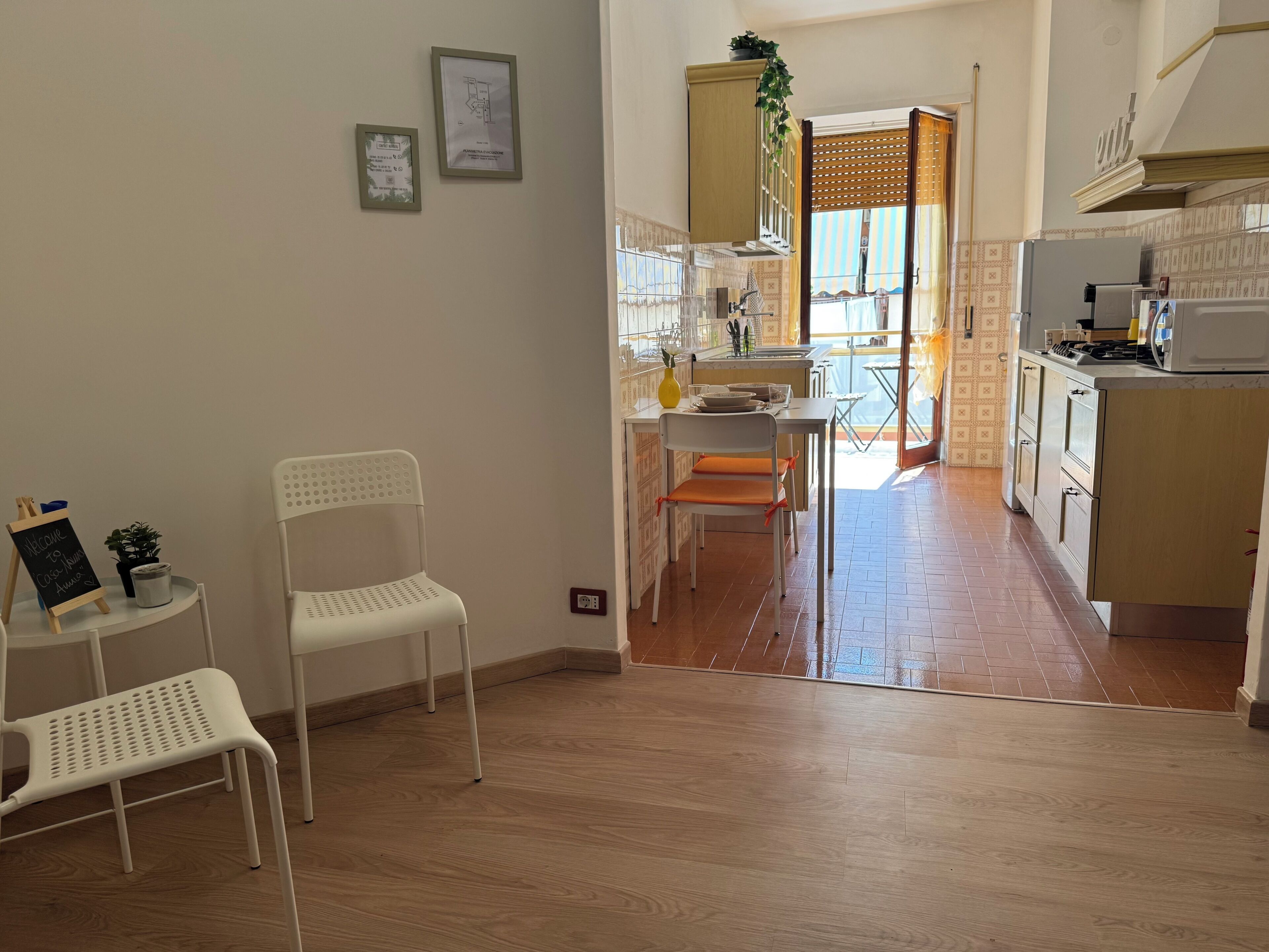 A kitchen with wooden flooring, a dining table, chairs, and a refrigerator.
