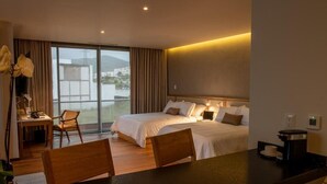 Una habitación de hotel con cama, escritorio, silla y cafetera.