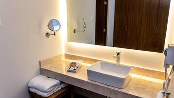 Un baño moderno con un espejo grande, un lavamanos blanco y un perchero para toallas.