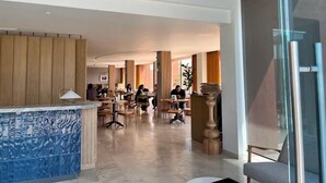 Un moderno vestíbulo de hotel con un mostrador de recepción de mármol, paneles de madera y una partición de vidrio.
