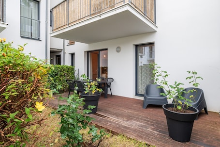 A modern outdoor patio with a wooden deck, potted plants, and outdoor furniture.. Apartment “Laïta - Stay in Quimperlé” with Private Terrace, Garden, and Wi-Fi