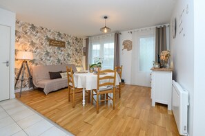 A dining area with a round table, chairs, a sofa, a lamp, and a radiator. - Apartment “Laïta - Stay in Quimperlé” with Private Terrace, Garden, and Wi-Fi (Quimperle)