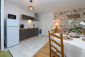 Una cocina moderna con microondas, estufa y cafetera, un comedor con mesa y sillas, y una pared decorativa con un letrero.