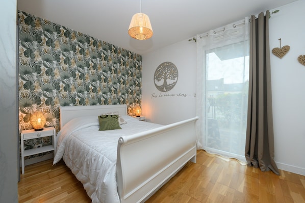 Un dormitorio con cama, lámparas de noche, una pared con diseño de árbol y una ventana con cortinas.