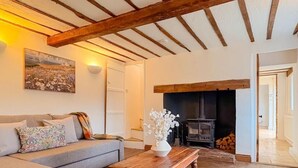 A cozy living room with a sofa, a wooden coffee table, and a fireplace. - Hainford Cottage (Waterloo)