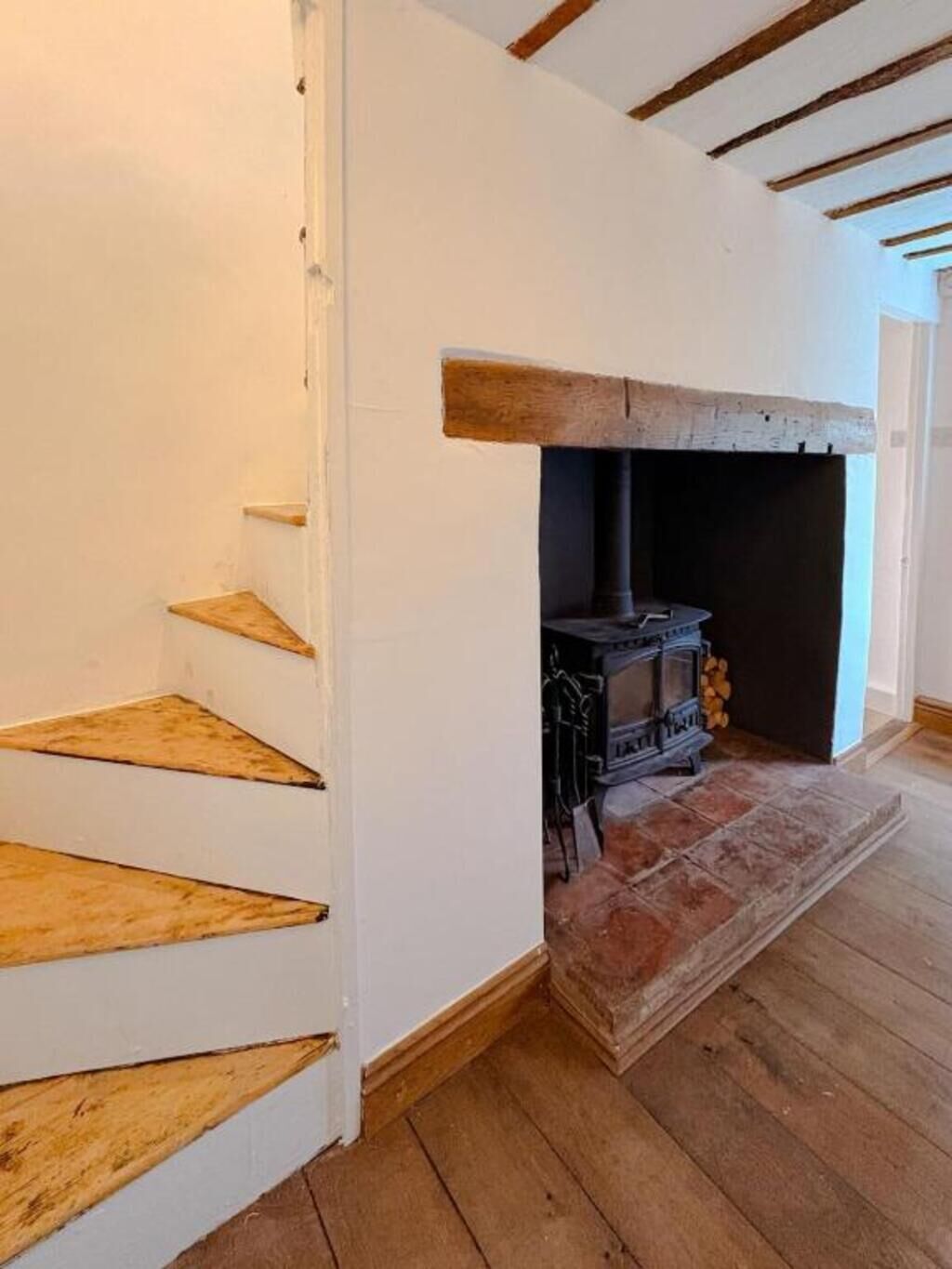 Una escalera con escalones de madera que conduce a una zona de chimenea con un hogar de piedra.