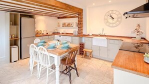 A modern kitchen with a wooden ceiling, white cabinetry, and a central island. - Hainford Cottage (Waterloo)