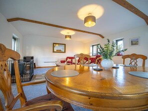 A dining area with a large wooden table, chairs, and a vase with plants. - Rural barn conversion in beautiful countryside (Stelling Minnis)