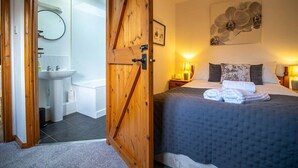 A bedroom with a bed, a nightstand, a lamp, and a painting on the wall. - Goose Shed | Rural Farm Cottage | Cosy Fire (Stelling Minnis)