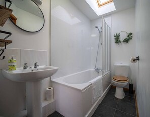 A bathroom with a white sink, a bathtub, a toilet, and a skylight. - Goose Shed | Rural Farm Cottage | Cosy Fire (Stelling Minnis)