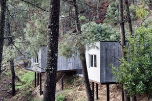 Træhuse med udvendige balkoner, omgivet af skov.