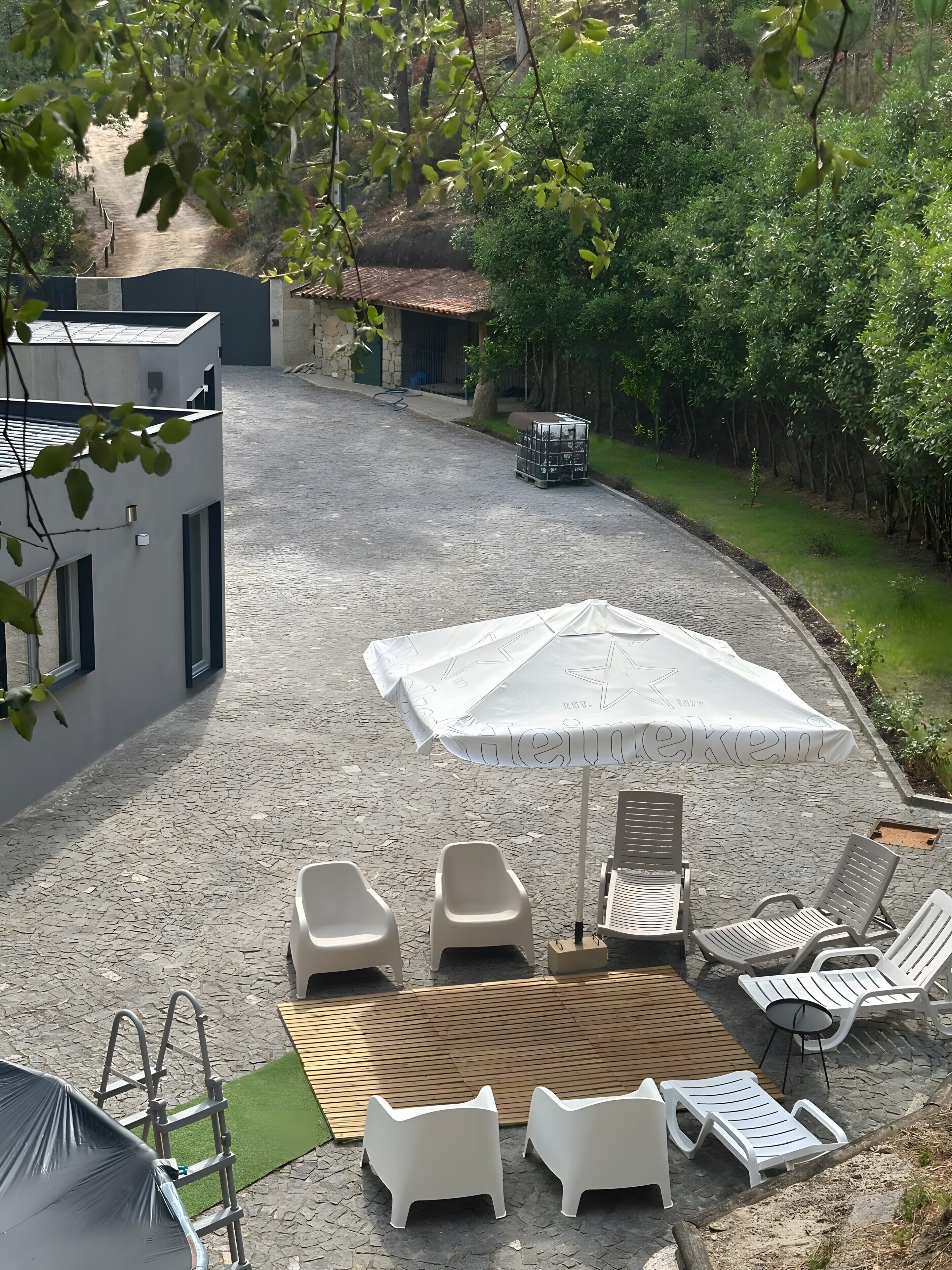 Eine Terrasse mit Sitzgelegenheiten, einem Sonnenschirm und einem Kiesweg, der zu einem Gebäude führt.