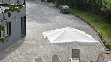 Eine Terrasse mit Sitzgelegenheiten, einem Sonnenschirm und einem Kiesweg, der zu einem Gebäude führt.