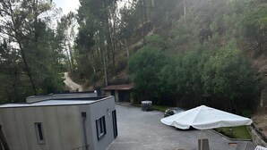 A swimming pool with a wooden deck, lounge chairs, and a white umbrella. - Casa do Martinho: Mountain Retreat with Lake View, Shared Terrace, and Wi-Fi (Vilar da Veiga)