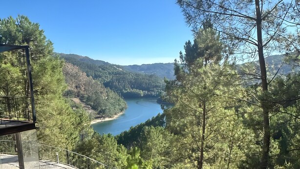 A stone-paved terrace with a metal railing overlooking a river and forested hills. - Casa do Martinho: Mountain Retreat with Lake View, Shared Terrace, and Wi-Fi (Vilar da Veiga)