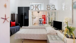 Makuuhuoneessa on sänky, televisio, peili ja ovi, jossa on merkintä ”DK83”.