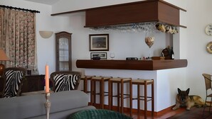 Un saló amb un sofà, un gos, una zona de bar de fusta i un candelabro.