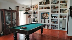 Una taula de bitlles en una habitació amb una prestatgeria, un armari i un rellotge a la paret.