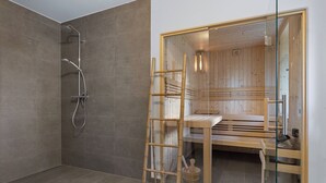 Ein Saunaraum mit einer Holzbank, einer Glastür und einem Duschbereich mit Glastür.