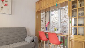 A living room with a grey sofa, red chairs, wooden cabinets, and a brick wall.