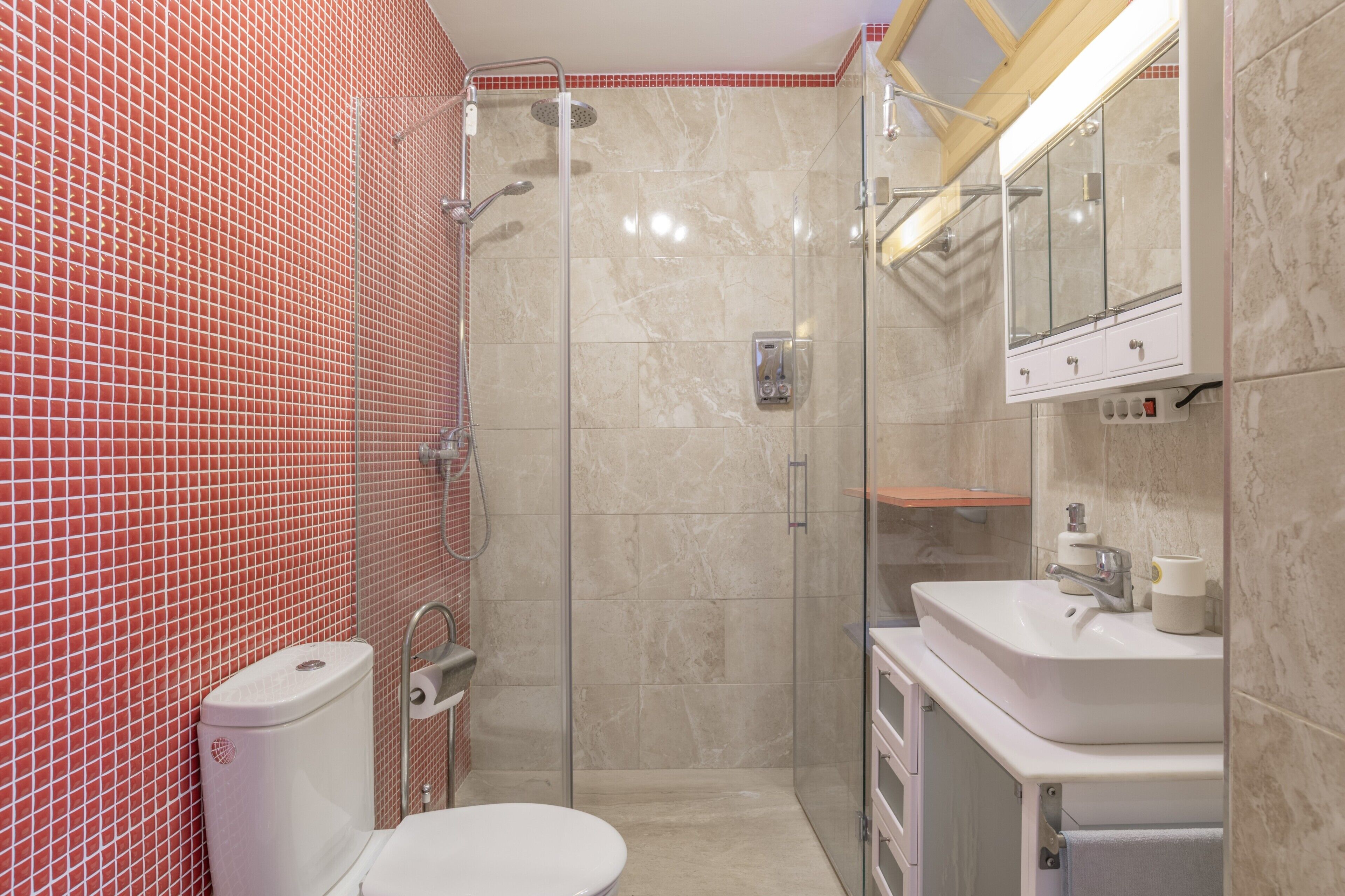 Een badkamer met toilet, douche, wastafel en spiegel.
