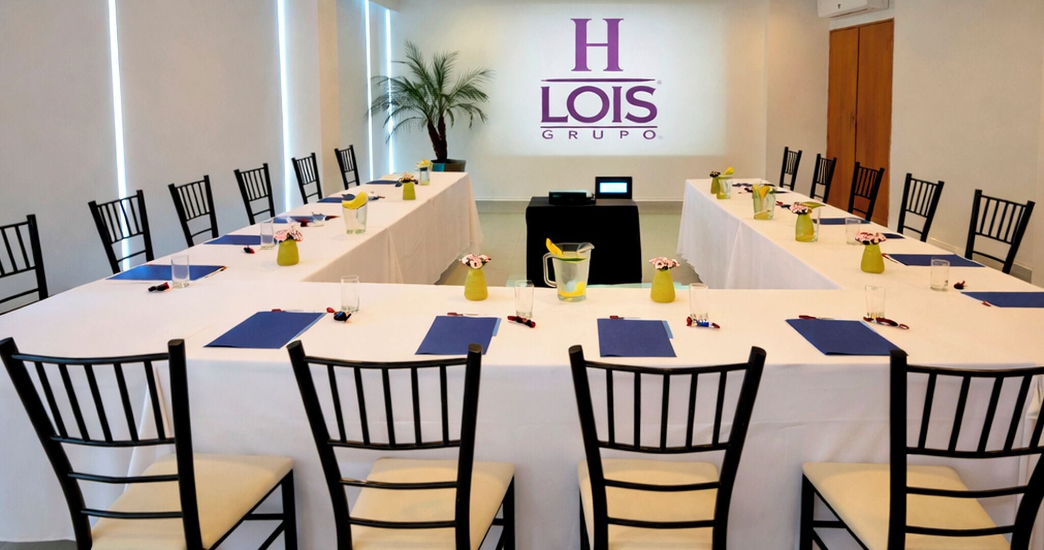 Une salle de conférence avec une longue table, des chaises et un logo sur le mur.