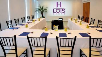 Une salle de conférence avec une longue table, des chaises et un logo sur le mur.