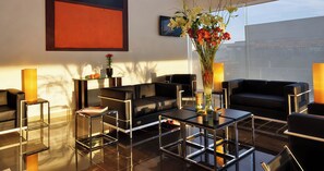A modern hotel lobby with black leather sofas, glass tables, and a large vase of flowers. - Hotel Lois Express Monterrey Aeropuerto La Fe (Apodaca)