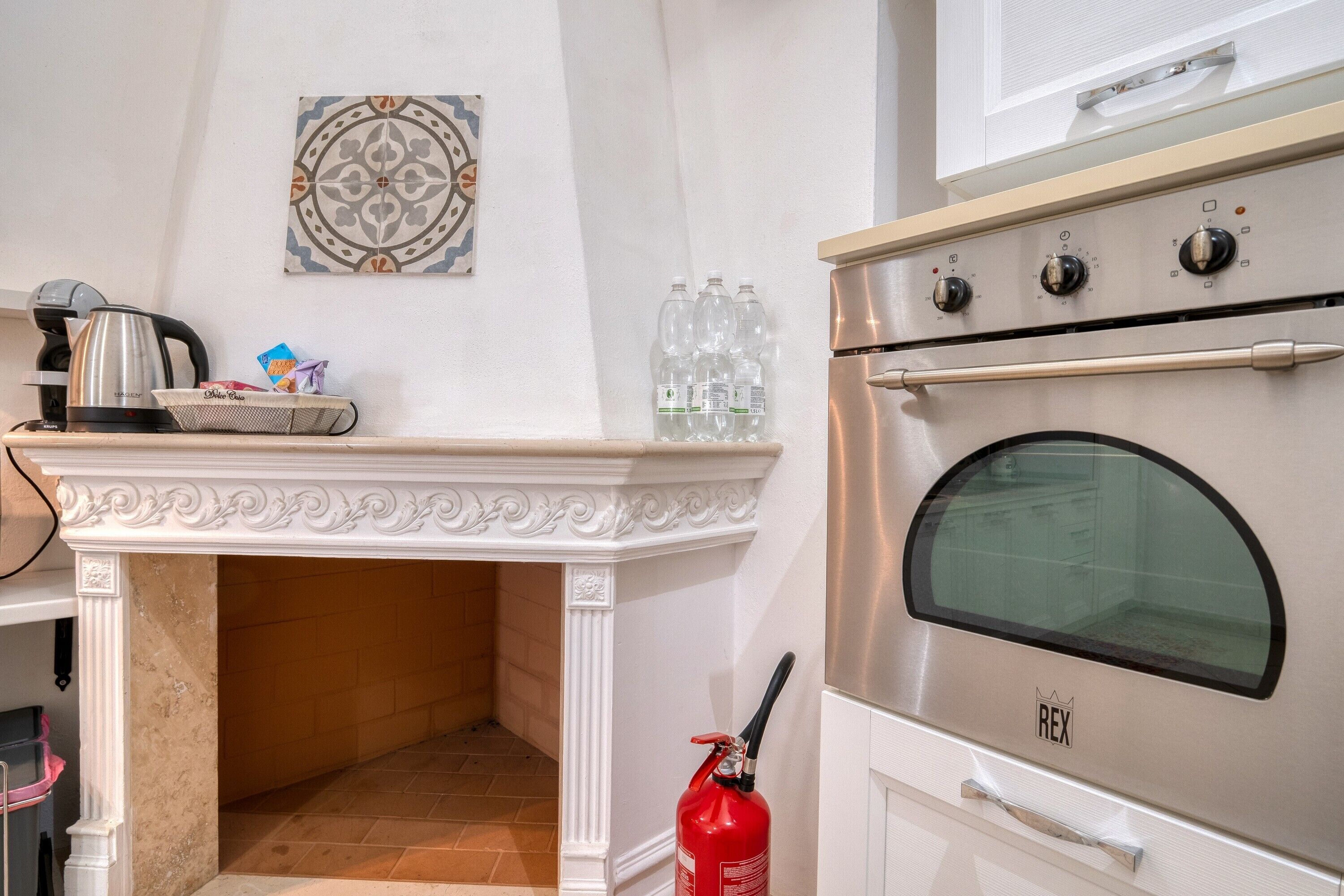 Una cocina con horno empotrado, cafetera y extintor.