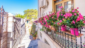 Une rue étroite avec un balcon orné de plantes et de fleurs en pot.